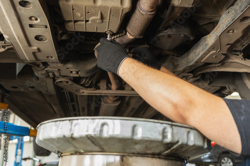Foto An auto mechanic tightens the oil drain plug in the crankcase of a car with a wr