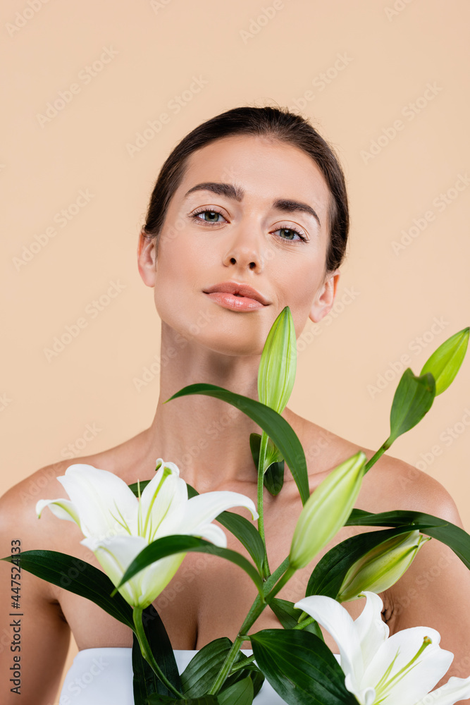sensual woman with fresh lily flowers looking at camera isolated on beige, beauty concept sensual woman with fresh lily flowers looking at camera isolated on beige, beauty concept