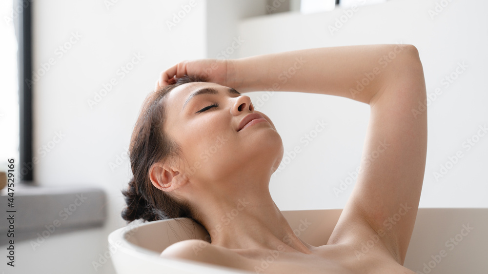 Happy relaxing serene woman resting in hot warm bath shower at home taking care of her skin hair. Spa beauty treatment, stress relief Happy relaxing serene woman resting in hot warm bath shower at home taking care of her skin hair. Spa beauty treatment, stress relief