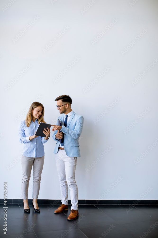 Young business people with tablet by the wall in the office Young business people with tablet by the wall in the office