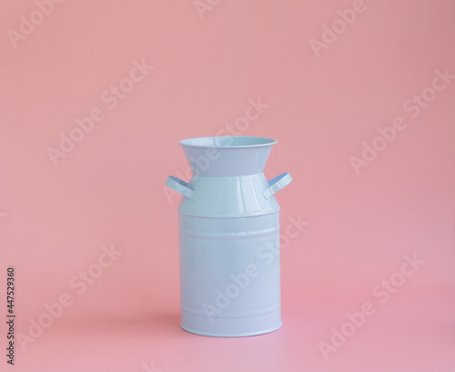 A blue enamel jug or can on a pink background