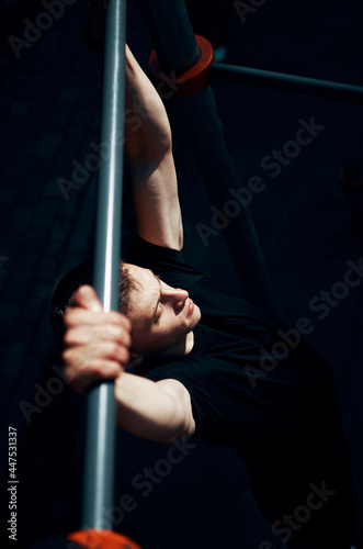 young handsome man performs pull-ups on horisontal bar