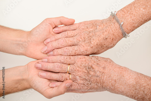 young person hands holding senior elderly people wrinkled hand close up