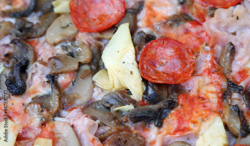 detail of pizza called capricciosa with mushrooms artichokes salami tomato sauce mozzarella in an Italian pizzeria