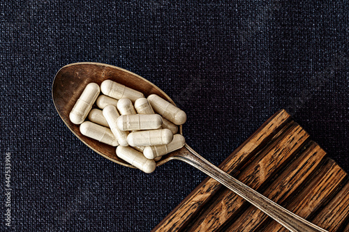 n-acetyl cysteine (NAC) supplement capsules  on iron spoon. mental wellbeing and personal health concept