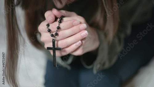 Wallpaper Mural Depressed lady brunette sits on grey sofa and prays holding black rosary in hands and kissing cross at home in morning closeup. Torontodigital.ca
