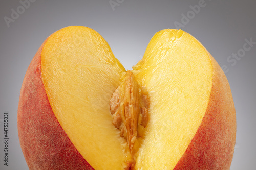 Fototapeta Naklejka Na Ścianę i Meble -  Peach with pulp and pit or kernel. Sliced peach pulp imitating the female sex. Сoncept of sexuality of forms, visual metaphors. Selective focus