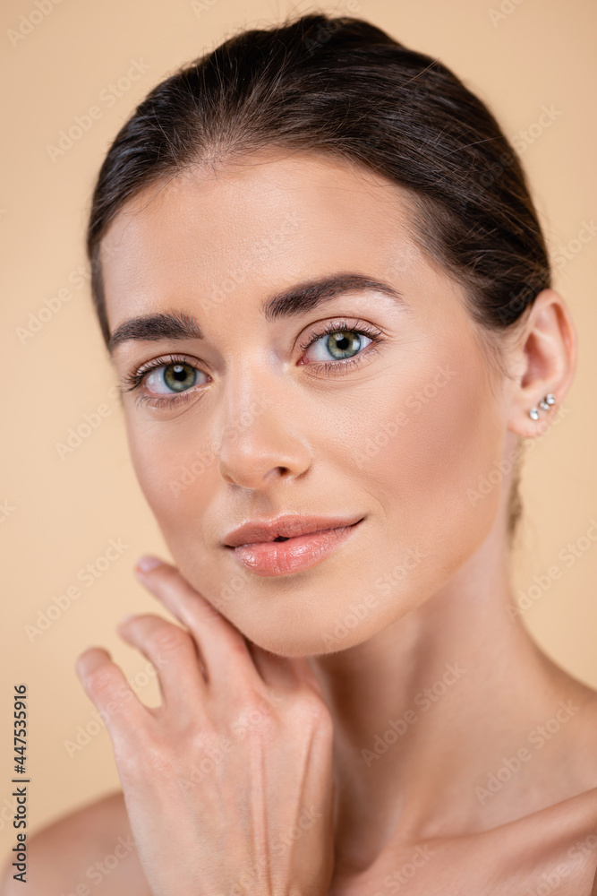 close up portrait of woman touching face while looking at camera isolated on beige, beauty concept close up portrait of woman touching face while looking at camera isolated on beige, beauty concept