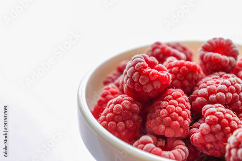Frozen raspberries in a bowl.  Fresh red raspberries isolation on white