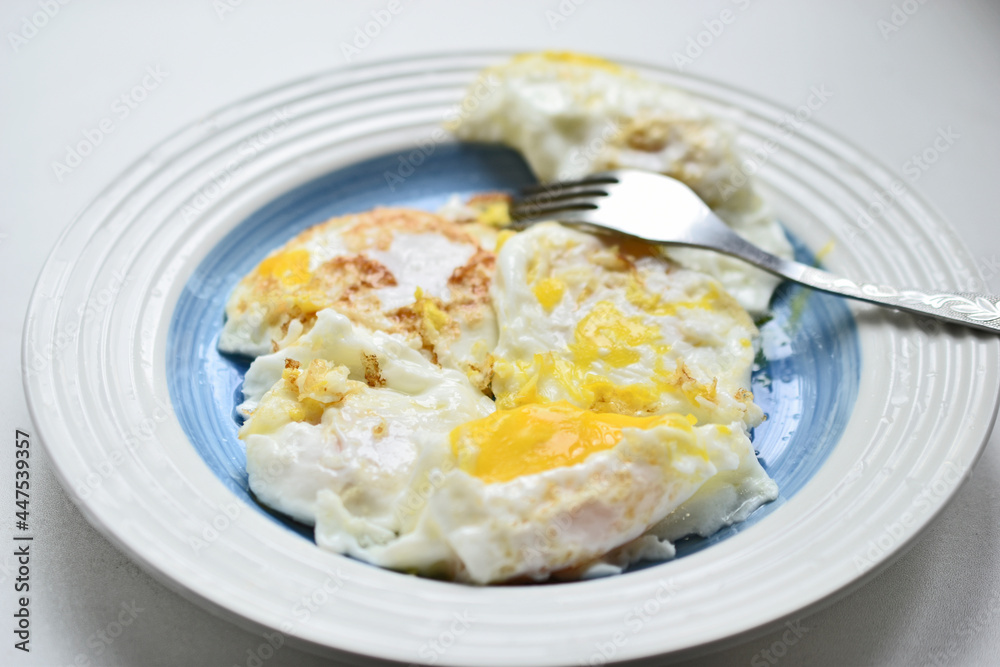 Fried eggs on a white plate with a fork