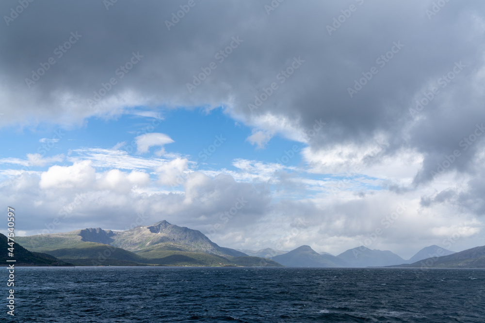rugged and wild coastline with mountains and stormy seas with whitecaps under and expressive cloudy sky