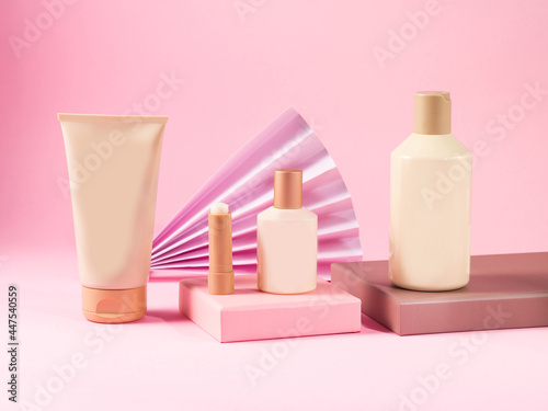 Geometric podium displaying set of body care generic bottles, tubes on pink background.