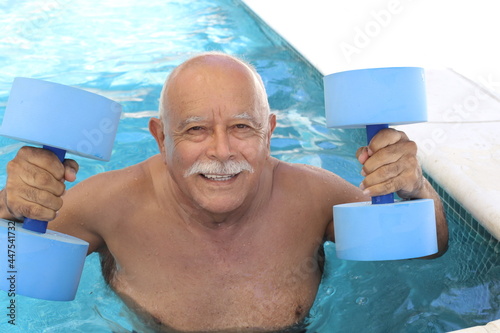 Senior man holding dumbbells in swimming pool photo