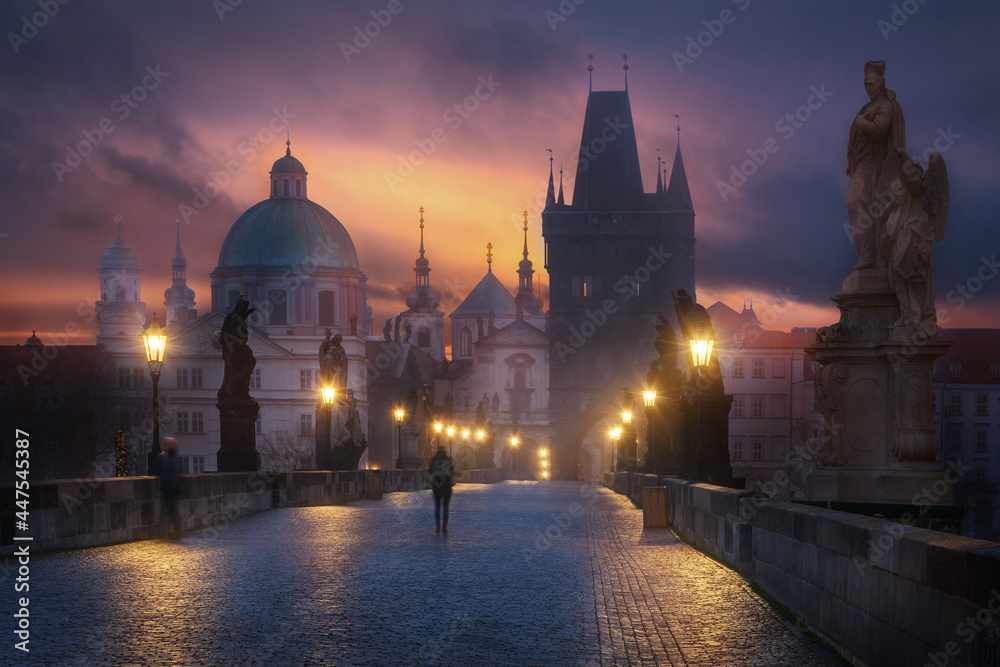 Mystic Charles bridge at night with a tourist in the foreground