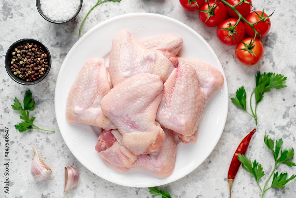 raw chicken wings on a white plate on a white stone background raw chicken wings on a white plate on a white stone background