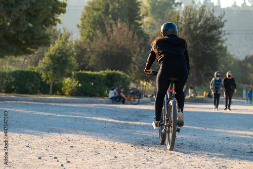 Fototapeta Naklejka Na Ścianę i Meble -  Young woman riding a bike at an urban park