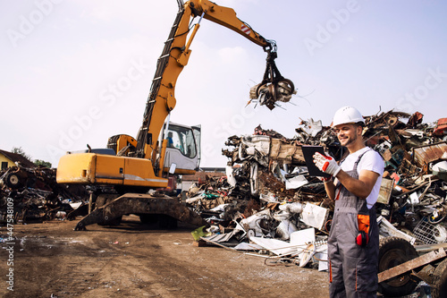 Man controlling process of industrial scrap metal lifting at junk yard. photo