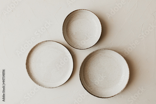 Three different size beige plate on beige background. Flat lay  top view. Natural color plates. Textured grainy pattern on the plates.