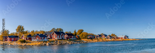 idyllic Baltic Sea panorama landscape with red cottages on the shoreline under a blue sky in autumn