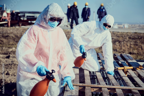 An employee in a suit, gloves, mask with equipment conducts surface sanitization