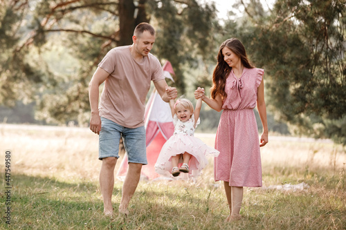 Portrait of happy family. Mom, dad and daughter walk in the park in nature. Young family spending time together on vacation, outdoors. The concept of summer holiday. Mother's, father's, baby's day