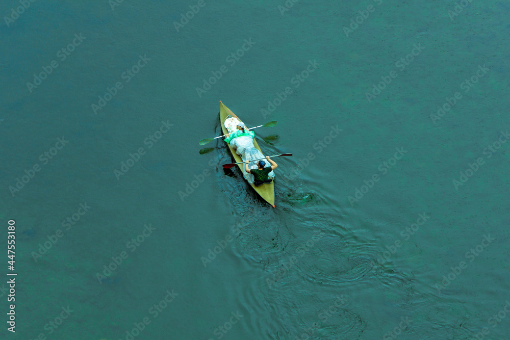 Kayaking on the high seas, drone photos. Shooting from a height. The couple is holding on to the oars in the boat. People in raincoats are rafting down the river.