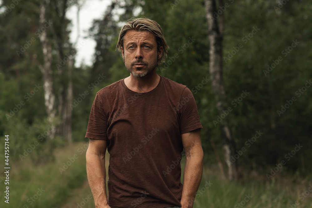 Blonde man with a stubble beard in a brown t-shirt on a forest p Blonde man with a stubble beard in a brown t-shirt on a forest p