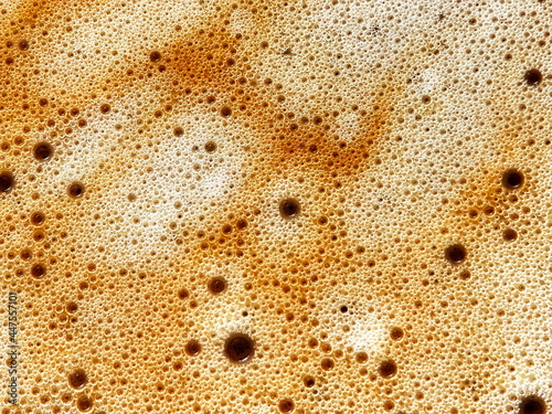 Closeup view of bubble on the top of a hot frothy coffee. No people.