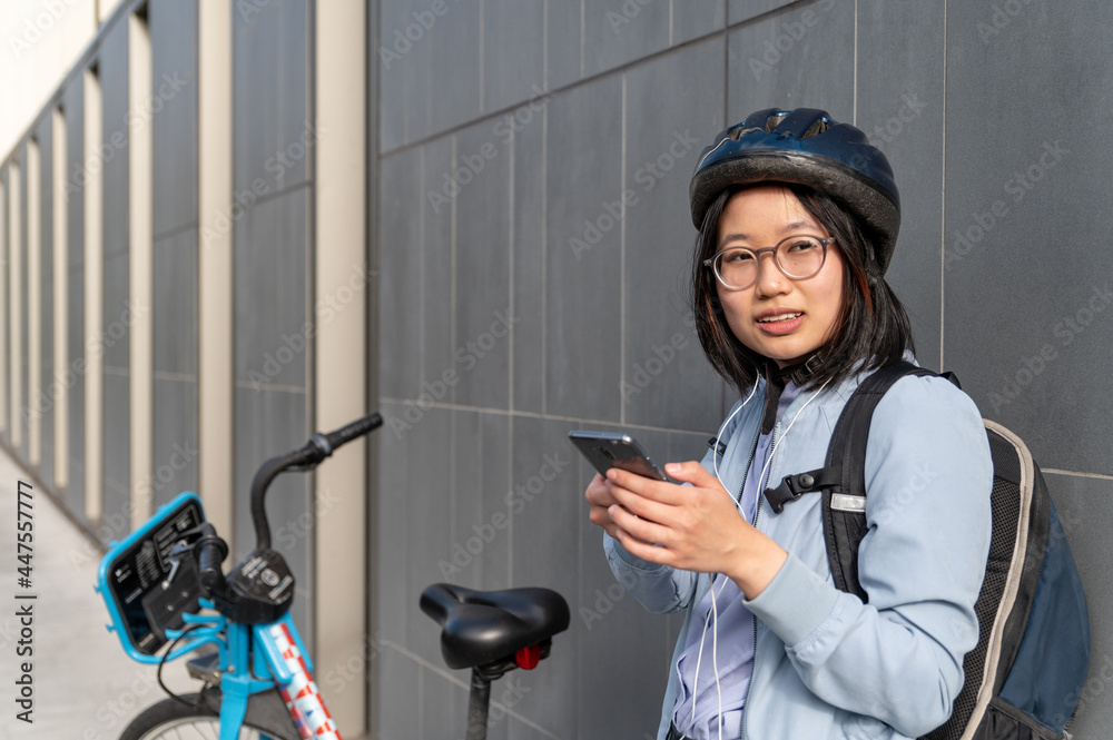 Young woman using cell phone standing next to bike share Young woman using cell phone standing next to bike share