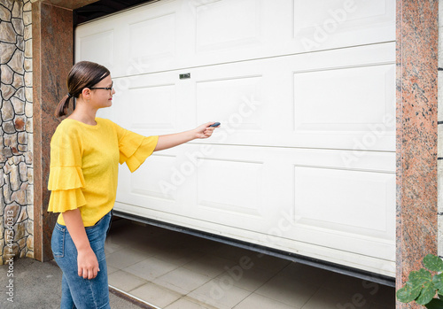 Garage door PVC. Girl or young woman use remote controller for closing and opening garage door photo
