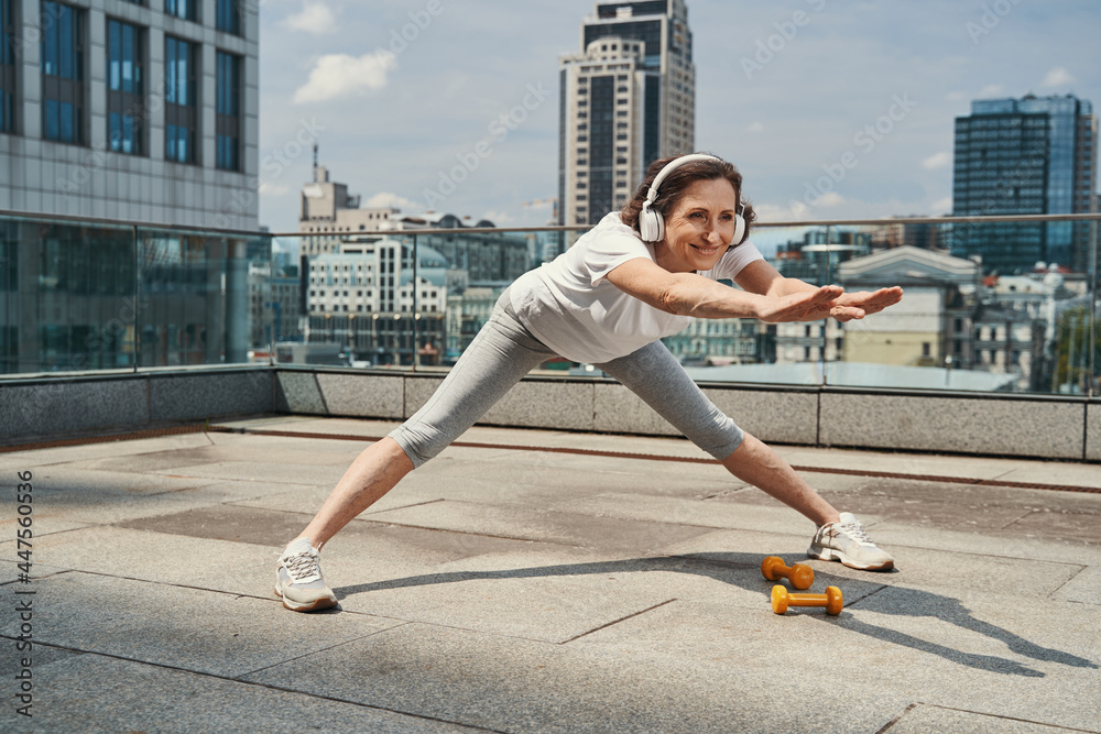 Jolly mature woman training flexibility on roof