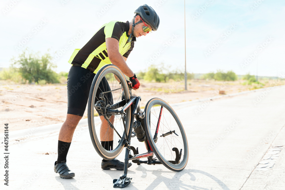 Naklejka premium Young man adjusting his bike to start training