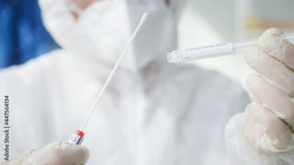Opening PCR test in laboratory, doctor looking at COVID-19 swab collection kit, lab worker wearing PPE medical suit, mask, gloves, holding test tube for taking OP NP specimen. Express covid analysis Opening PCR test in laboratory, doctor looking at COVID-19 swab collection kit, lab worker wearing PPE medical suit, mask, gloves, holding test tube for taking OP NP specimen. Express covid analysis