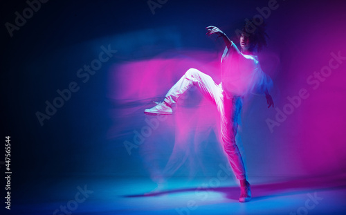 Fototapeta Naklejka Na Ścianę i Meble -  Dancing sportive female in colorful neon light. Expressive contemporary dance. Studio photography with long exposure