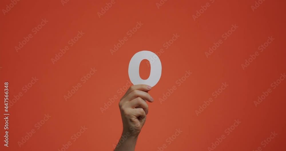 Number zero in hand. Arm showing digits, null numeral made of carved paper for voting or learning