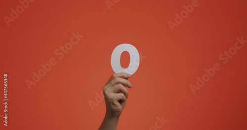 Number zero in hand. Arm showing digits, null numeral made of carved paper for voting or learning
