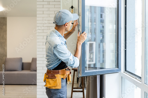 Young handyman male worker repair window