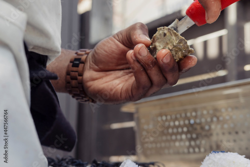 Man shucking oysters in front of grill