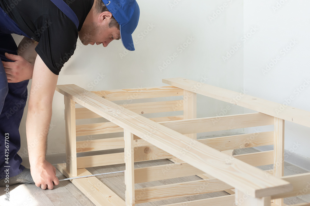 A carpenter measures a wooden structure. Carpentry work