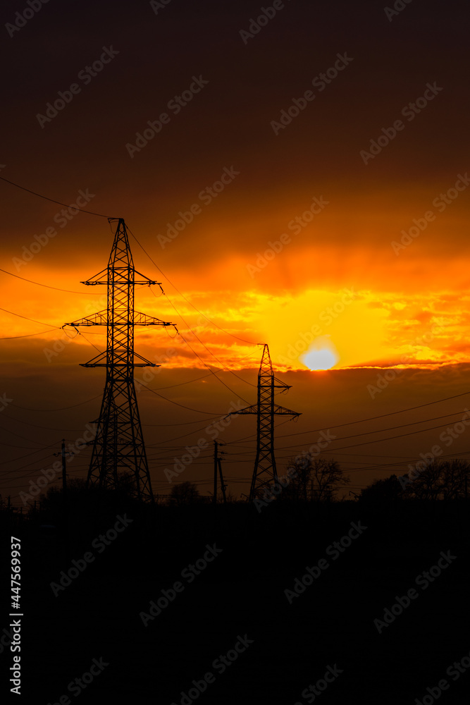 High voltage power line at sunset. Silhouettes of the metal pillars