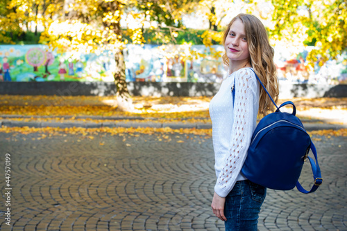 Happy teenage school child hold blue backpack on autymn city background, knowledge day. photo