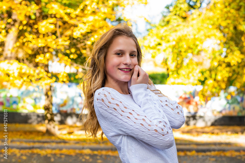 Beautiful cute teenage girl walking outdoors in autumn. Smiling girl young woman enjoying autumn weather.