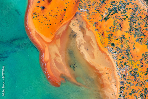 Abstract aerial view of blue-green water in shifting red deposition of sediment gradually moving through alluvial plains of Francois Peron National Park in Western Australia. photo