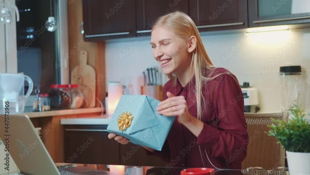 Medium shot of Pretty woman showing her gift to friends by online video call. She sitting in the kitchen at home. Medium shot of Pretty woman showing her gift to friends by online video call. She sitting in the kitchen at home.