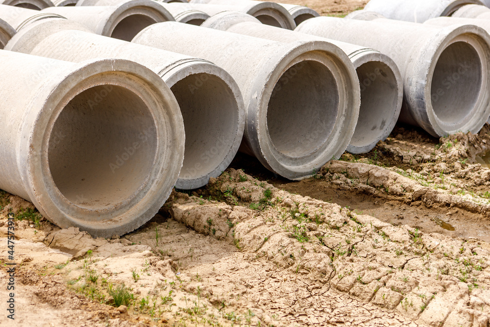 Concrete pipes for the construction of objects lie on the ground. Concrete pipes for the construction of objects lie on the ground.