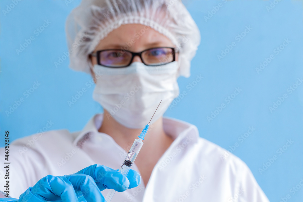 Doctor wear eyeglasses and disposable face mask holding raised up needle. Infection prevention concept.