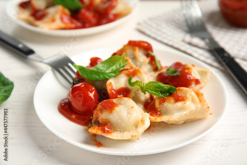 Tasty ravioli with tomato sauce served on white table