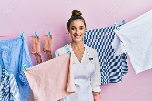 Beautiful brunette young woman washing clothes at clothesline with a happy and cool smile on face. lucky person.