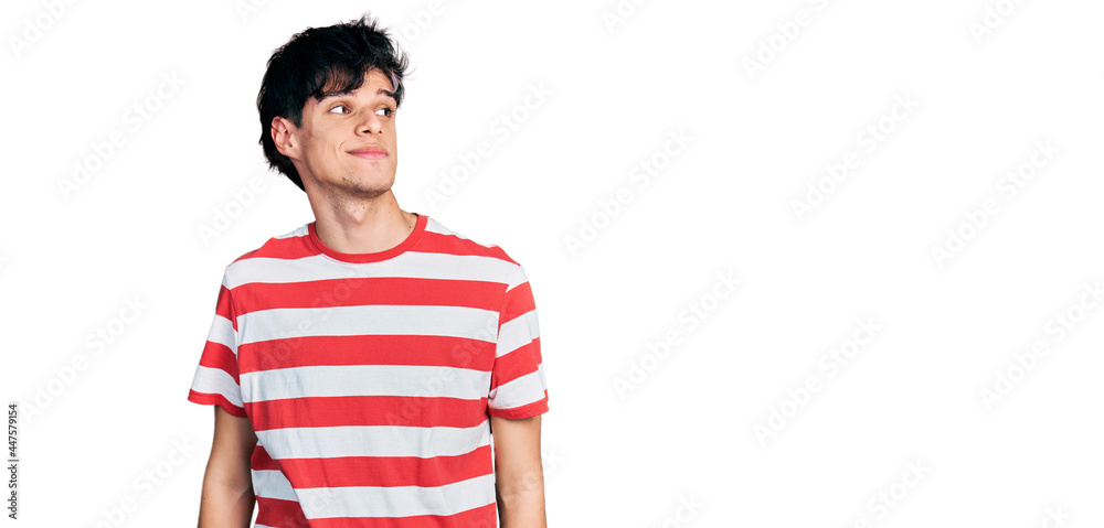 Handsome hipster young man wearing casual striped t shirt smiling looking to the side and staring away thinking. Handsome hipster young man wearing casual striped t shirt smiling looking to the side and staring away thinking.