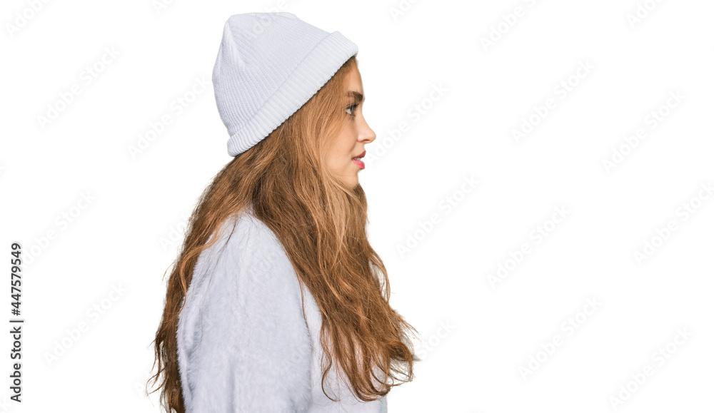 Young caucasian girl wearing wool sweater and winter cap looking to side, relax profile pose with natural face with confident smile. Young caucasian girl wearing wool sweater and winter cap looking to side, relax profile pose with natural face with confident smile.